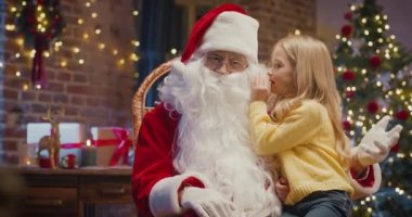 Sana söyleyeceğim ama bunu sır olarak sakla. Noel Baba 'yla sırlarını paylaşan küçük sarışın kızın portre görüntüsü.