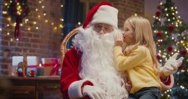 Sana söyleyeceğim ama bunu sır olarak sakla. Noel Baba 'yla sırlarını paylaşan küçük sarışın kızın portre görüntüsü.