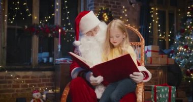 Mutlu kız çocuğu Noel Baba 'ya sarılıyor ve kitabı faiziyle okuyor. Mutlu çocuk Noel Baba 'yla vakit geçiriyor. Tatil kavramı