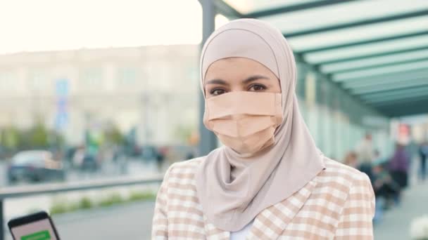Μουσουλμάνα γυναίκα με ιατρική μάσκα που δείχνει ένα Διεθνές Πιστοποιητικό Εμβολιασμού σε smartphone. Κωδικός QR του εμβολιασμένου ατόμου στην εφαρμογή για κινητά τηλέφωνα. Κοντινό πλάνο. Ψηφιακό διαβατήριο υγείας — Αρχείο Βίντεο