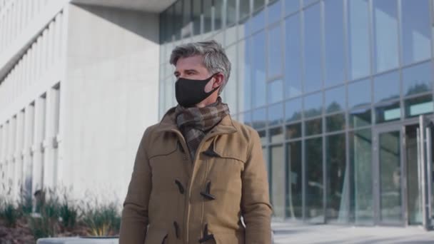 Ik beschermde mijn leven. Bewegingscamera zicht van de blanke senior man poserend bij het beschermende masker en kijkend naar de camera terwijl hij zich veilig voelt — Stockvideo