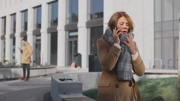 Cintura para arriba de mujer madura tosiendo en la calle de la ciudad. Retrato de mujer enferma de mediana edad de pie y conversando en su smartphone al aire libre — Vídeos de Stock