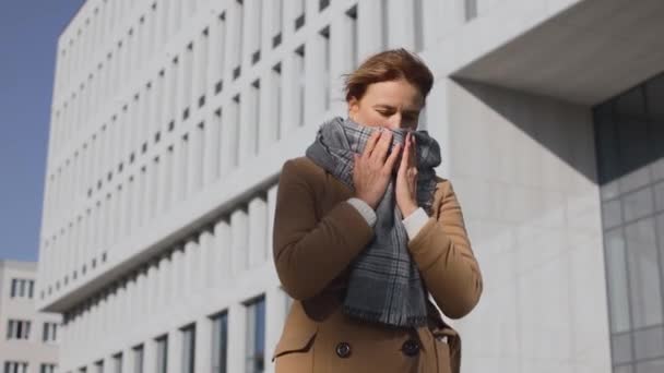 Close up portrait of unwell caucasian woman standing on street and covering mouth with hand while coughing. Virus infection concept — Stock Video