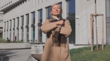 Kalın ceketli yaşlı, donmuş kadın. Güz sokağında soğuktan donarken elbiselerine sarılmış güzel bir kadın. Isınma konsepti