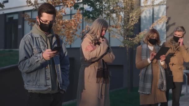 Повнометражний погляд на людей, які носять захисні маски, дивлячись на кашлю жінки і відходячи на безпечну відстань від неї під час пандемії ковадла 19 — стокове відео