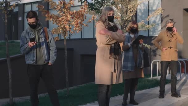 Volledig zicht op de oudere vrouw met het beschermende masker hoesten terwijl ze op straat staat op de veiligheidsafstand van een ander volk tijdens de covid 19 pandemie — Stockvideo