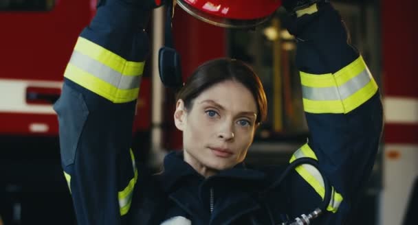 Крупним планом хороша жінка пожежник знімає шолом і посміхається до камери у пожежній машині. Портрет . — стокове відео