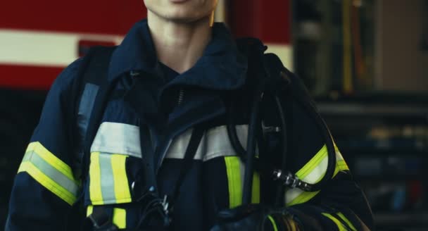 Camera zoomen uit van de prachtige glimlachende blanke vrouwelijke brandweerman in het uniform op de rode vuurbaan achtergrond. Portret. Sluiten.. — Stockvideo