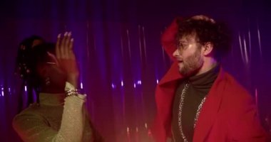 Kırmızı ceketli ve gümüş zincirli genç adam, balık ağlı bluzlu ve güneş gözlüklü genç bir kadınla yüz yüze dans ediyor. Kız ve erkek geceyi gece kulübünün renkli ışıklarıyla geçirirler..