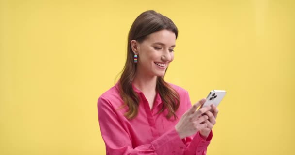노란색 배경에 스마트폰으로 네트워크를 탐색하면서 즐거운 여성의 모습을 클로즈업해 십시오 — 비디오