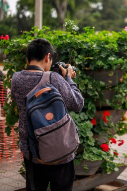 Sırt çantası takan Perulu genç adam profesyonel kamerasıyla fotoğraf çekiyor.