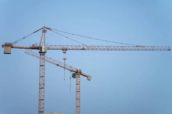 Açık mavi gökyüzü üzerinde inşaat vinci hareketsiz duruyor, inşaat ekipmanları, şehir binası