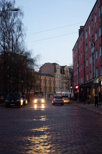 Araba, kaldırımlı bir yolda yanan farlarla, uyuyan ağaçlarla, dar bir Avrupa caddesinde sürüyor. Kalininingrad Şehri 15 Kasım 2021