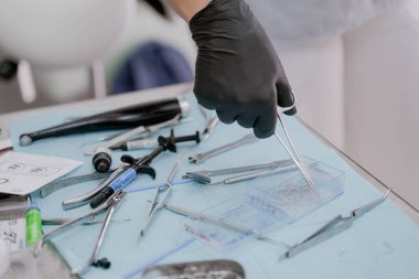 Siyah eldivenli bir ortodontist eli cımbızla diş teli takmak için metal bir bağ alır. Anapa 24 Eylül 2021