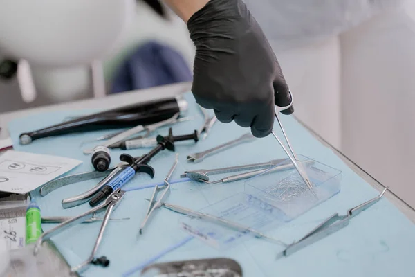 Siyah eldivenli bir ortodontist eli cımbızla diş teli takmak için metal bir bağ alır. Anapa 24 Eylül 2021