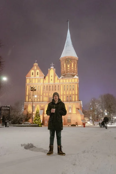 Aydınlanmış şehir binasında gece bir turist çekiliyor, kış dönemi, kar, aydınlatılmış şehir ışıkları. Yeni yıl atmosferi