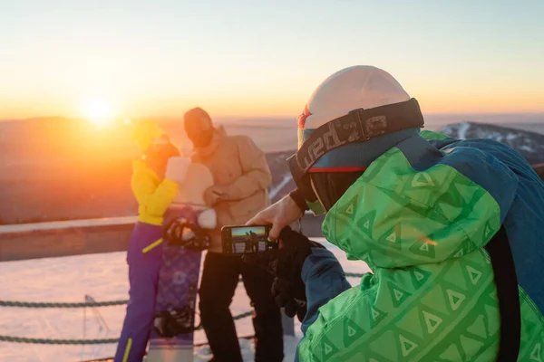 Cep telefonuyla anı dondurur, gün batımında bir dağda, kış manzarasında, dışarıda iyi vakit geçirir.