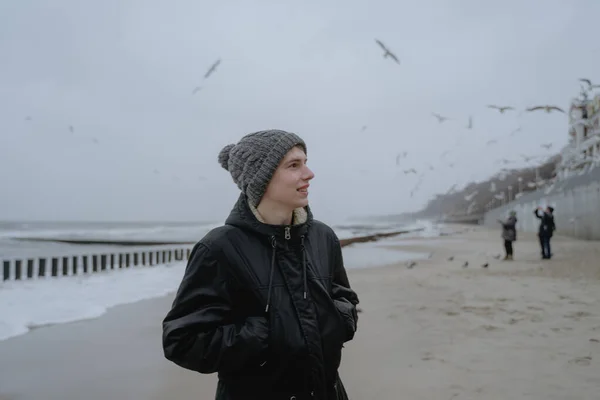 teenager looks to the side with an admiring face, enjoys sea nature, pork birds fly in the background