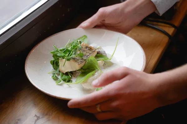Tahta bir masaya bir tabak balık koyar, otlarla süslenmiş güzel bir restoran.