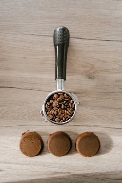 Kahve çekirdeklerinden yapılmış organik vücut fırçası, tahıllarla dolu bir tutucu, yanında işlenmiş kahve tabletleri, üst görünüm.