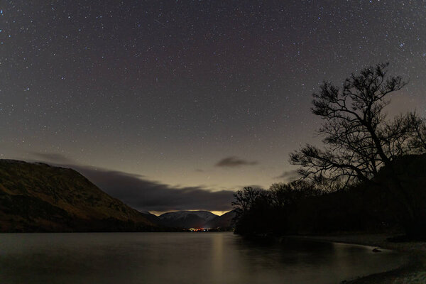 A View of the night sky over Ullswater in the English Lake District with snow capping the distant mountains