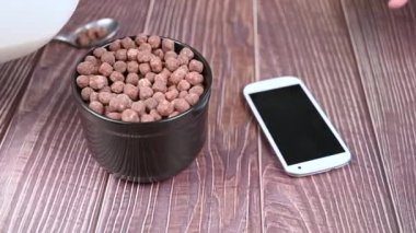 Siyah bir fincanda çikolatalı gevrek toplarına süt dökmek. Hızlı sabah sağlıklı kahvaltı konsepti.