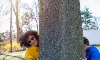 Gün batımına karşı parkta oğluyla saklambaç oynayan Latin Amerikalı genç bir annenin portresini yakından çek..