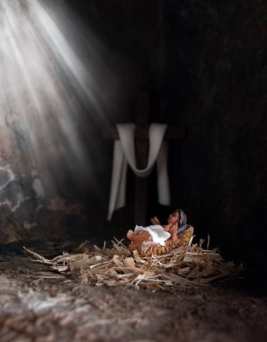 Christmas time. Baby Jesus in a Manger, Rays of light shining him with wood Cross background.