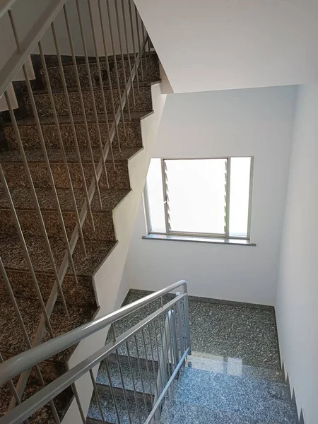 Steps of stairs and railings in a residential building. Marble staircase in condominium with iron railing.