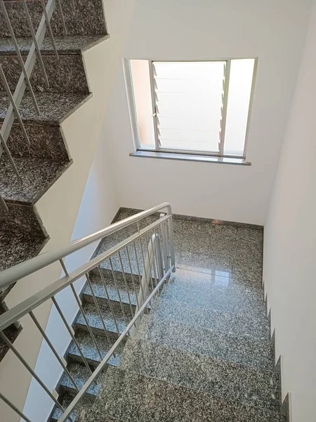 Steps of stairs and railings in a residential building. Marble staircase in condominium with iron railing.
