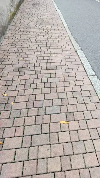 Sidewalk Close-up - Street in the City. Long section of the pavement, visible gneiss, at the roadside.