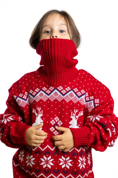 Psotna twarz dziewczynki pół zerka z kołnierzyka świątecznego swetra z reniferem, odizolowana na białym tle — Zdjęcie stockowe
