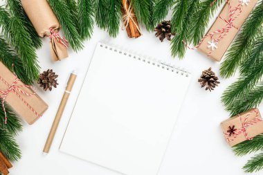 Noel arkaplanı boş beyaz not defterinden dilek listesi ve hediye kutuları, koniler ve tarçınlı köknar dallarının çerçevesi.
