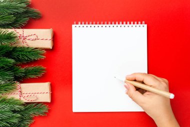 Noel Baba 'ya mektup yaz Noel ağacı dalları ve hediye kutularıyla süslenmiş kırmızı masaya.