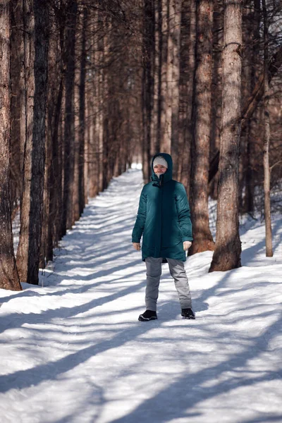 Ung kvinna står på vägen bland träd. Vit kvinna gå på solig frostig dag i skogen efter tungt snöfall — Stockfoto