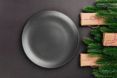 Siyah boş tabağa yakın plan yatar siyah izole arkaplan üzerinde fotokopi alanı ve köknar dalları ve hediye kutularından yapılmış Noel süslemeleri ile