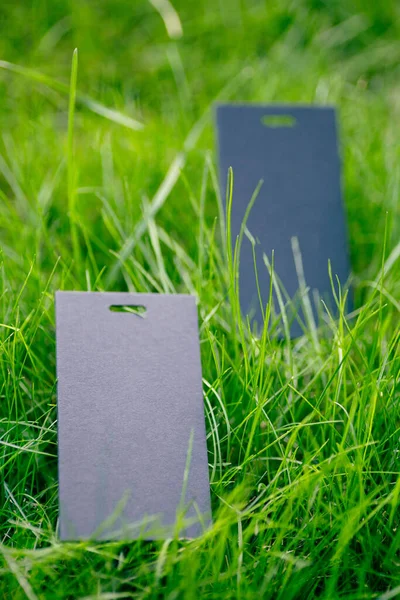 Kreative Layout-Komposition Rahmen aus grünem Rasen mit zwei schwarzen Preisschildern für Kleidung für Fabrik Seitenansicht und Kopierraum für Logo — Stockfoto