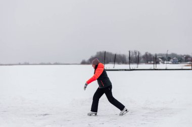 Güzel bir kadın göle biniyor. Kışın giyinmiş genç bir kadın, dondurucu soğukta artistik patinaj yapmaktan hoşlanıyor.