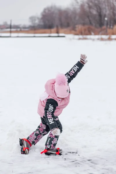 Маленька дівчинка на прогулянці. Дитина в теплому костюмі вчиться кататися на льоду замерзлого озера — стокове фото