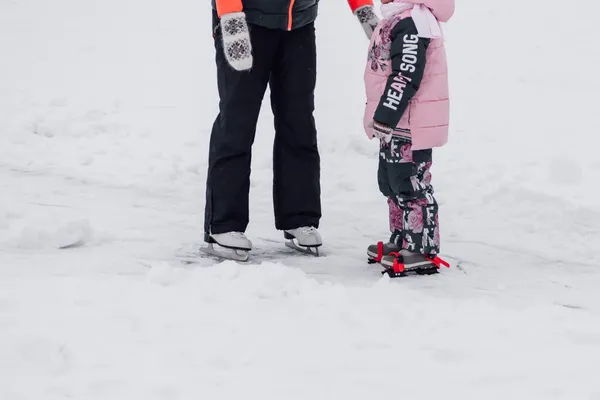 Nahaufnahme menschlicher Beine und Eiskunstlaufschuhe. Junge Frau und kleines Mädchen laufen im Winter in der Natur Schlittschuh — Stockfoto