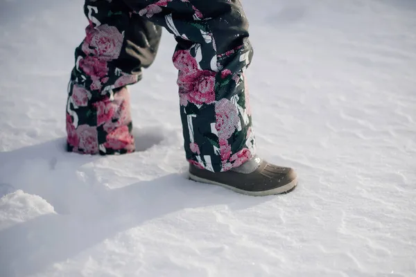 Close-up de pernas de crianças em terno de inverno. Vista lateral das pernas da menina andando pela neve em botas de feltro, caminhar no inverno no dia ensolarado gelado após a queda de neve — Fotografia de Stock