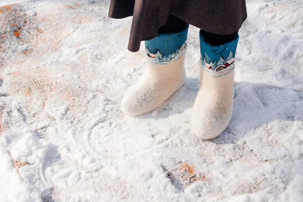 Süslü beyaz keçeli çizmeler. Keçeli çizmeler içinde insan ayaklarının yakın plan çekimi ve taze karla kaplı halının üzerinde durmak, geleneksel ekolojik halı temizleme yöntemi. — Stok fotoğraf
