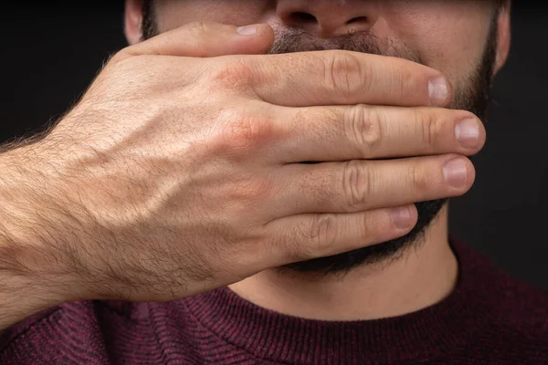 Zblízka portrét vyděšeného mladého muže zakrývající s rukou ústa izolované na černém pozadí. Lidské emoce čelí výrazu. — Stock fotografie