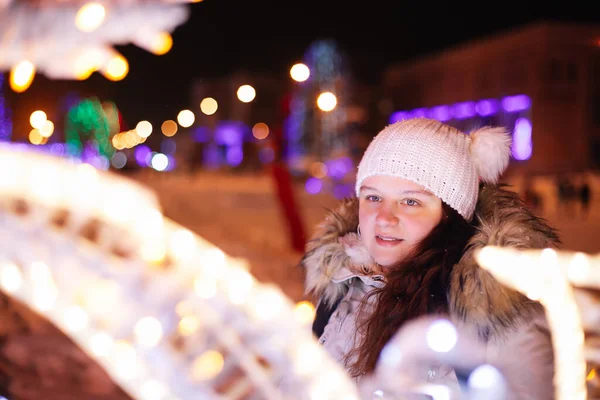 Jonge vrouw wandelen in de markt versierd met feestelijke lichten in de avond, vieren geluk in de grote stad, vakantie doorbrengen met haar familie — Stockfoto