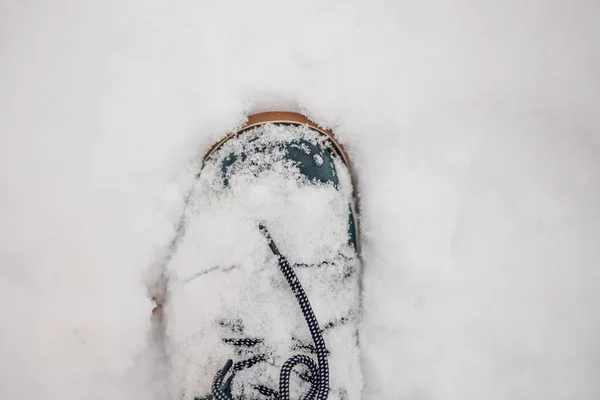 Closeup photo of winter blue warm boot with laces out in snow making footprint on ground covered with snow. Astonishing background full of white and show — Fotografia de Stock