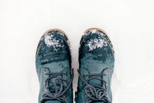 Foto de close-up de inverno simetricamente colocar botas azuis quentes com atacadores para fora na neve fazendo pegada no chão coberto com neve. Fundo surpreendente cheio de branco e show — Fotografia de Stock