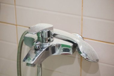 Lavabodaki yenileme çalışmaları ve arka planda pembemsi duvarlar olduğu için musluk ve duş başlığının üzerindeki toz ve toz. Kirlenmeye yol açan yenileme süreci 