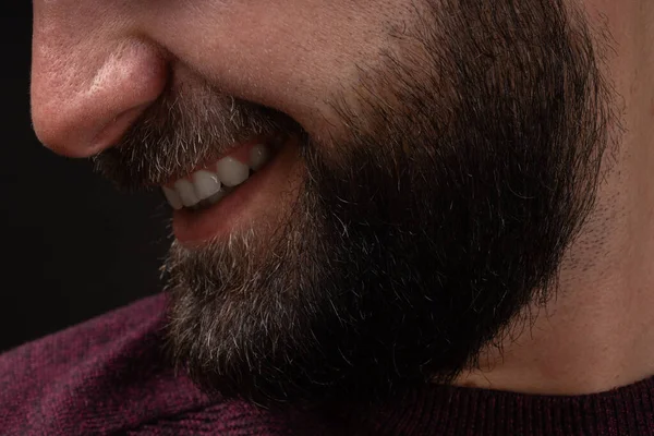 Detail-up portrét v profilu mladého usmívajícího se, šťastný muž s tlustým černým vousem a knírem na černém pozadí — Stock fotografie