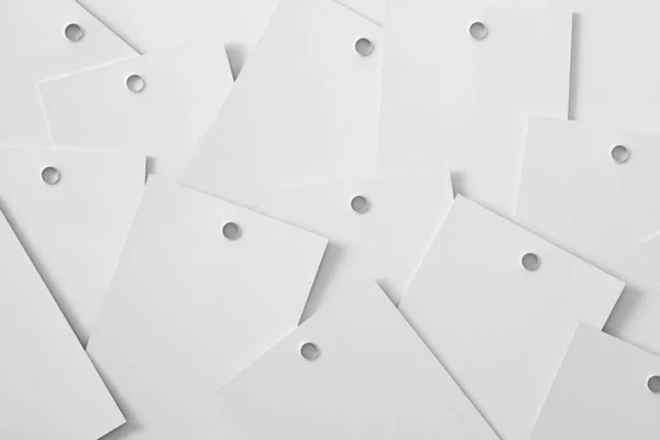 Abstract background with heap of scattered white cardboard tags for clothes with small holes in upper part of each put onto each other and having soothing effect — стоковое фото