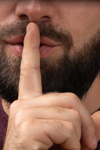 Close up cropped image of bearded man showing silence gesture with finger over lips asking to be quiet. Silence and secret concept. — Foto Stock